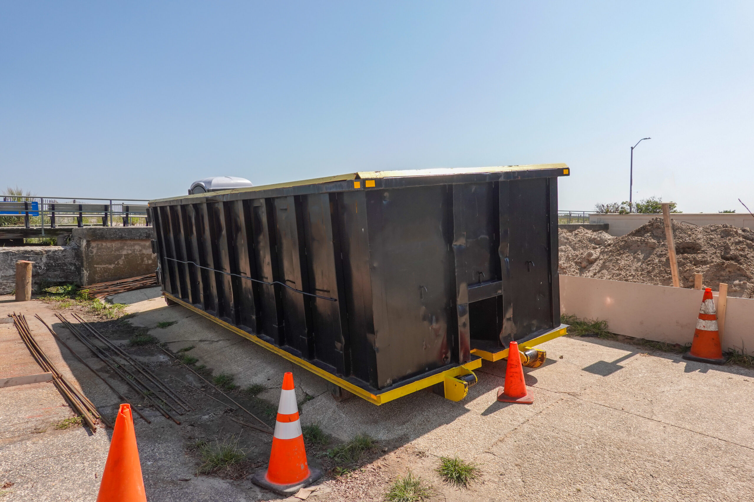 An empty black dumpster is seen at a construction site by a boardwalk at the beach; Shutterstock ID 1842073129; purchase_order: Limited 4/15; job: ; client: ; other: